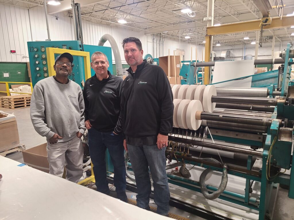 Three people in front of Converted Products machinery