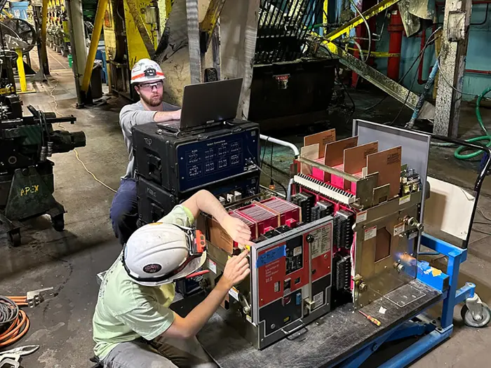 Two men in hard hats doing electrical circuit testing