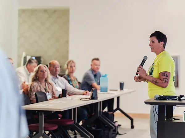 woman speaking in front of the people at a conference