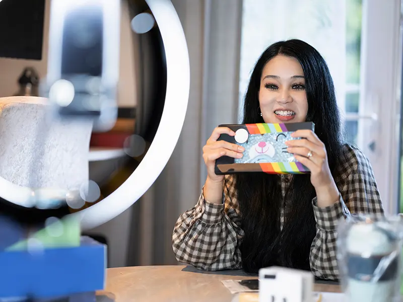Woman sitting in front of ring light holding package