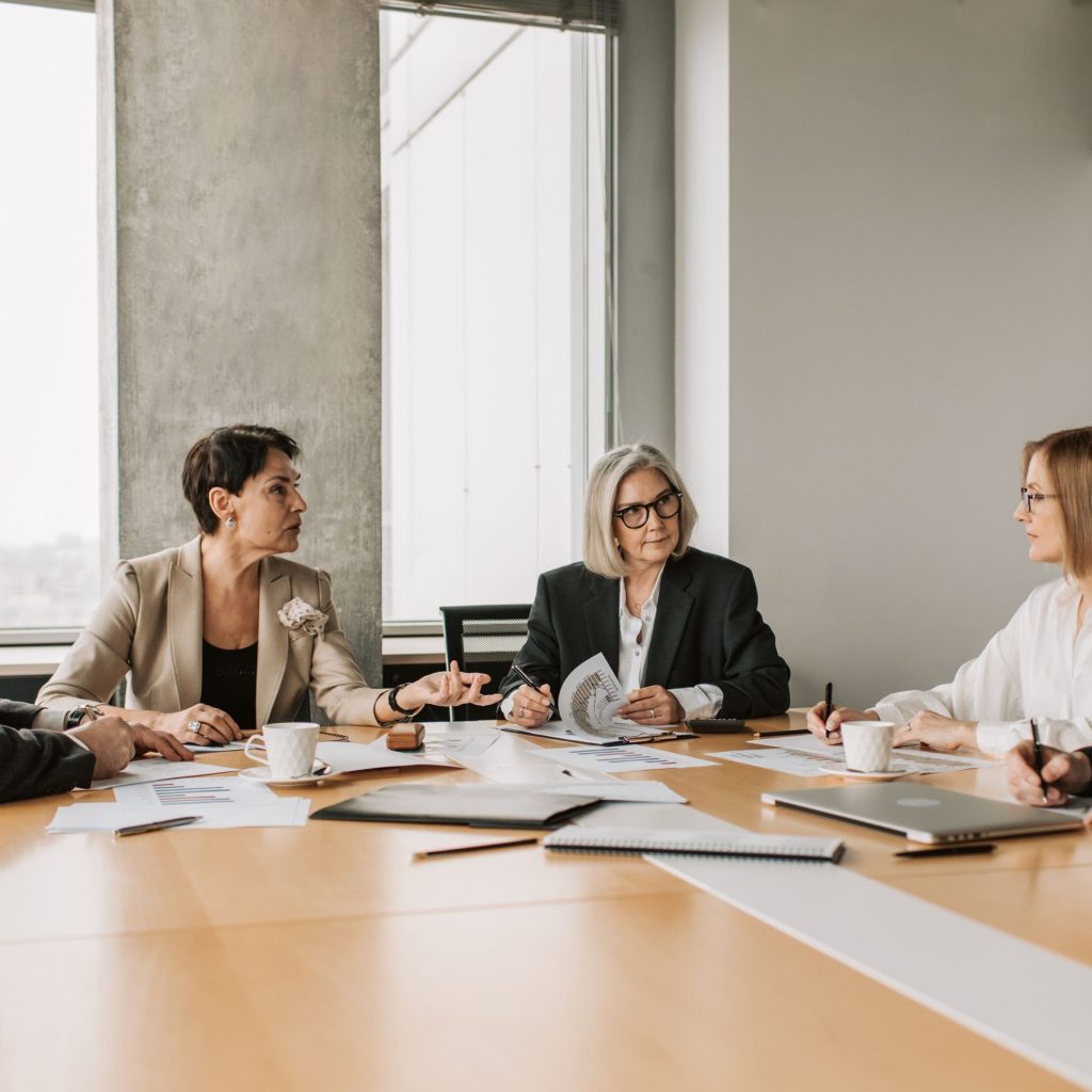 Five business professionals engaged in a meeting in a modern office setting, discussing documents and ideas.